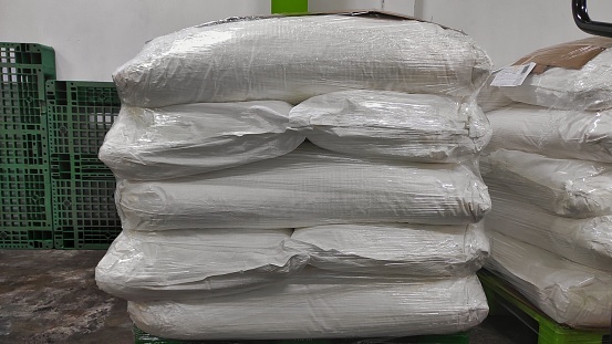 Industrial object background of several pile of dried shredded sacks coconut cover with plastic after production process in the factory
