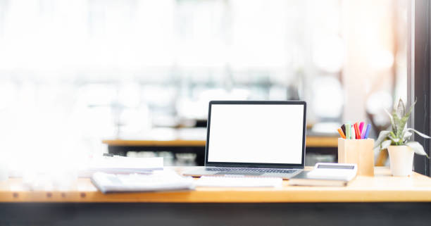istock Laptop screen, Laptop Computer, notebook copy space, and eyeglasses sitting on a desk in a large open plan office space after working hours 1417867472