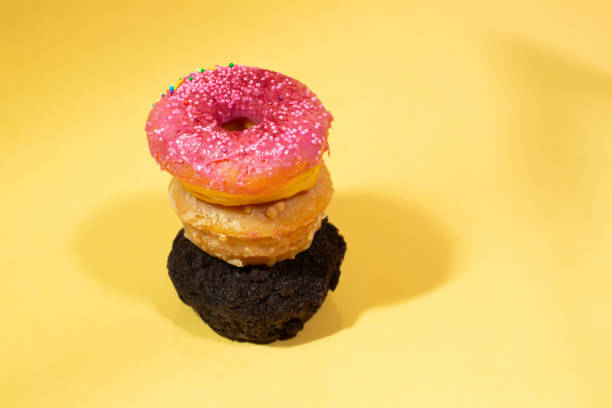 istock Donuts with candles on a yellow background with flying powder. Birthday. 1417871233