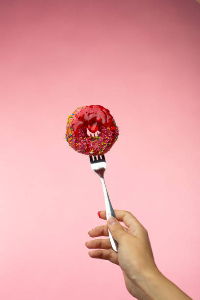 istock A glazed donut is pricked on a fork. Jam is poured on a donut 1417872520