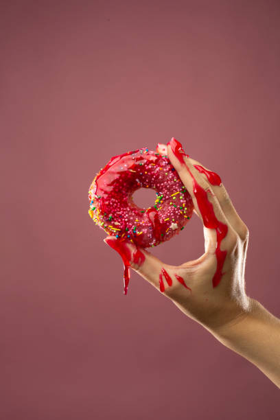 istock A hand in jam holds a donut with icing 1417872550