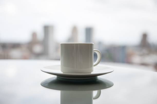 istock Closeup of a white coffee cup reflected on a glass table against a blurred background 1417878029