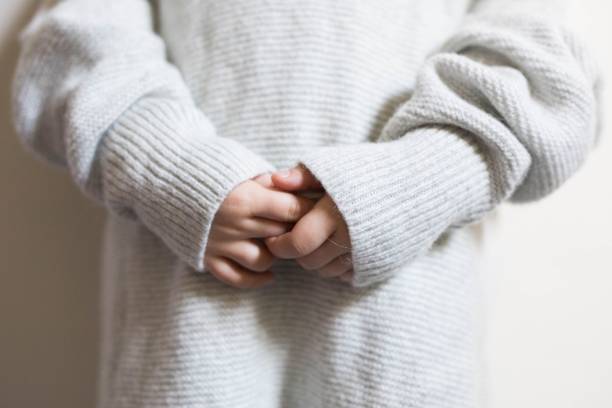 istock Small child in a light gray woven jumper holding hands clasped 1417879052
