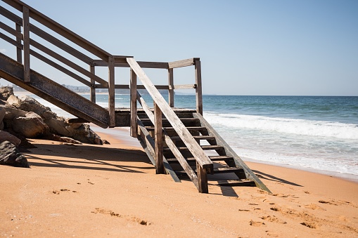 A closeup shot of a wooden staircase in the sandy beach in the daylight