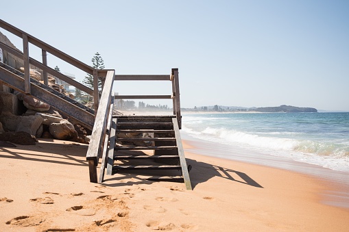 A closeup shot of a wooden staircase in the sandy beach in the daylight