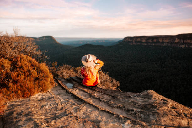 woman looks out over the mountains in the late afternoon sun - travel scenics landscape observation point imagens e fotografias de stock