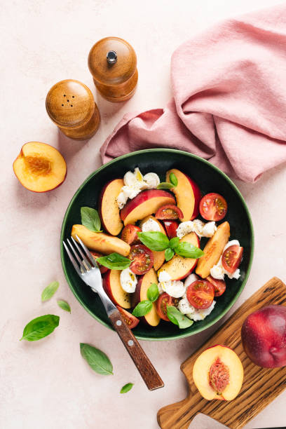 Healthy summer fruit and cheese salad Healthy summer fruit and cheese salad with peach, mozzarella, cherry tomatoes and basil. Top view vinegar stock pictures, royalty-free photos & images