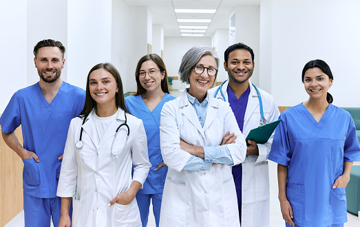 Medical teamwork. Portrait of happy multiethnic medical team standing in hospital corridor