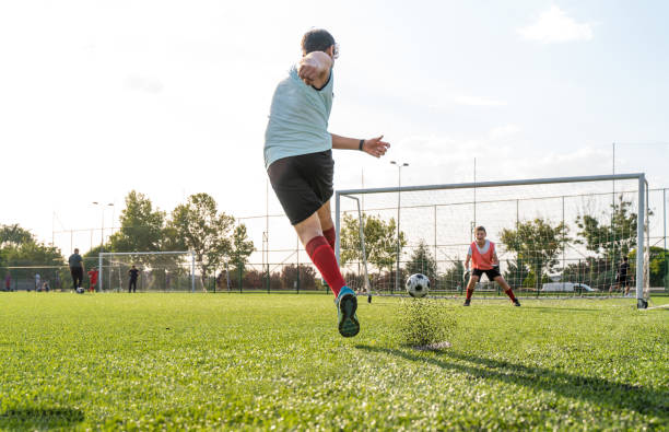 teenager boy practicing penalty kicks and playing soccer. male goalkeeper playing football with friend teenager boy practicing penalty kicks and playing soccer. male goalkeeper playing football with friend teen goalie stock pictures, royalty-free photos & images