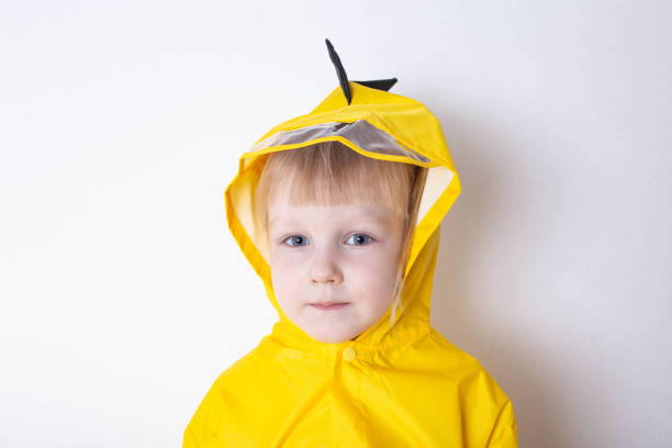 portrait of a little girl aged 3 years in a hooded yellow raincoat on a white background. the concept of bad weather and autumn. close-up - child caucasian little girls 3 4 years imagens e fotografias de stock