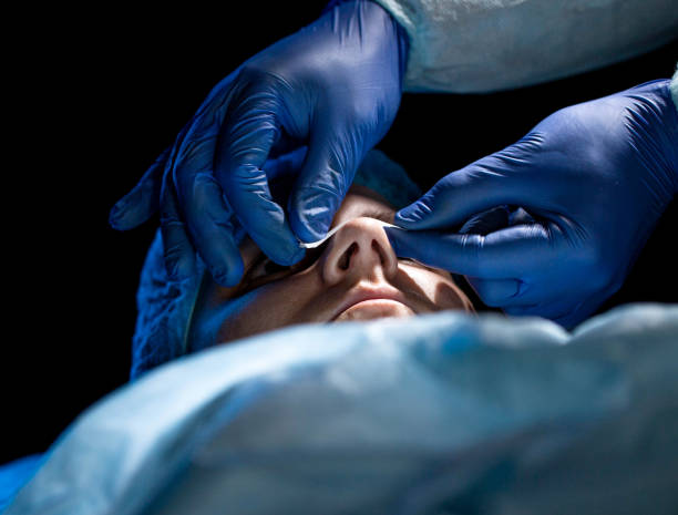 Doctor cosmetologist performs plastic surgery to correct the shape of the nostrils and nose of the patient's girl. Rhinoplasty, elimination of the siddle shape of the nose Doctor cosmetologist performs plastic surgery to correct the shape of the nostrils and nose of the patient's girl. Rhinoplasty, elimination of the siddle shape of the nose. Close-up septum stock pictures, royalty-free photos & images