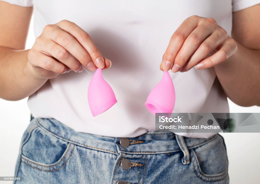 The girl holds in her hands two pink menstrual cups to collect the discharge during menstruation. Modern replacement for female pads and tampons, gynecological. Close-up The girl holds in her hands two pink menstrual cups to collect the discharge during menstruation. Modern replacement for female pads and tampons, gynecological Close-up Stock Photo