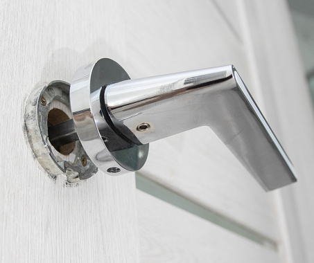 Chrome doorknob and keyhole on a white wooden door