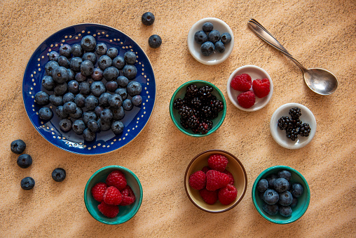 Blackberries, raspberries and blueberries in small bowls - from above