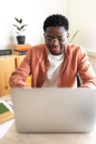 istock African American male college student studying at home using laptop. Vertical image. 1417897181