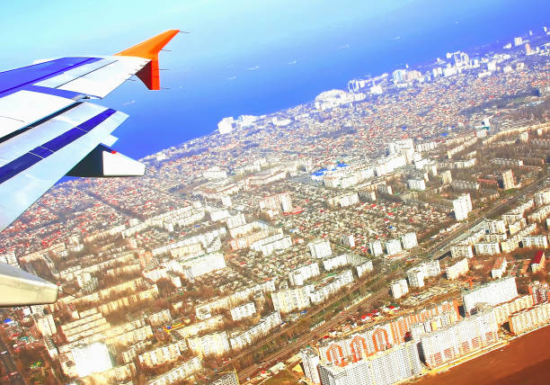 Aircraft wing in flight, view from the window of the plane flying over cities land, soft focus