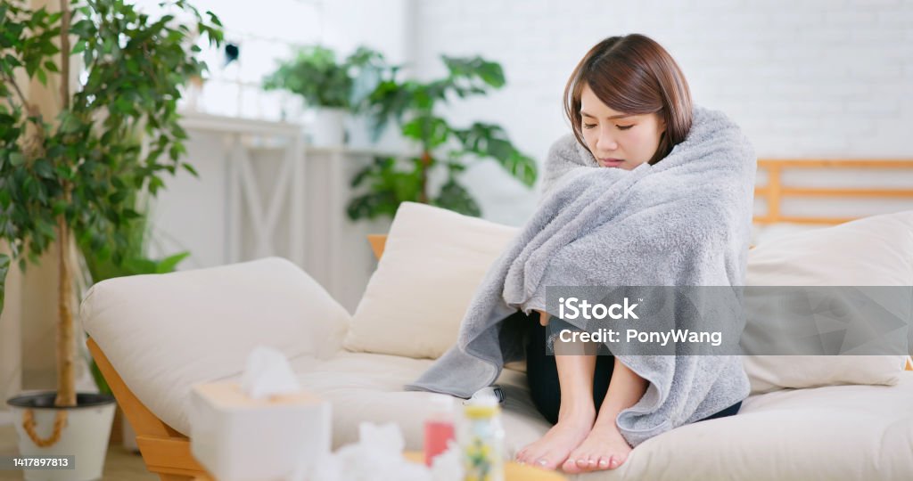 woman is sick asian woman cowerig covering in the blanket feeling uncomfortable at home Frozen Stock Photo