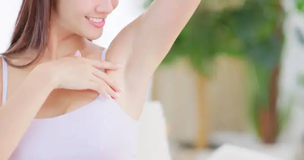 close up asian girl touching her armpit being satisfied at home