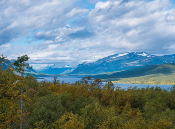 istock Lapland landscape with beautiful river Lulealven, snow capped mountain, birch tree and footpath of Kungsleden hiking trail near Saltoluokta, north of Sweden wild nature. Summer blue sky 1417899010