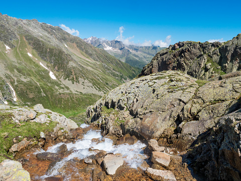 View of wild spring stream at green alpine mountain valley at Stubai hiking trail, Stubai Hohenweg, Summer rocky landscape of Tyrol, Stubai Alps, Austria.