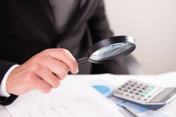 istock Businessman examining document with magnifying glass 1417899439