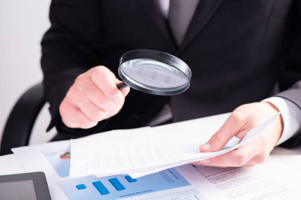 istock Businessman examining document with magnifying glass 1417899667