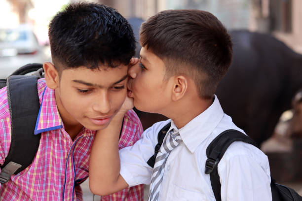 Gossip student telling secret to his friend in village, Panipat, Haryana, India.