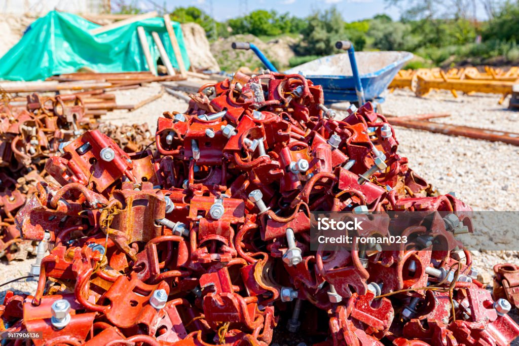 Pile of dismantled scaffolding joints scattered on the groundView on heap of disassembled steel scaffolding joint on construction site. View on heap of disassembled steel scaffolding joint on construction site. Bolt - Fastener Stock Photo