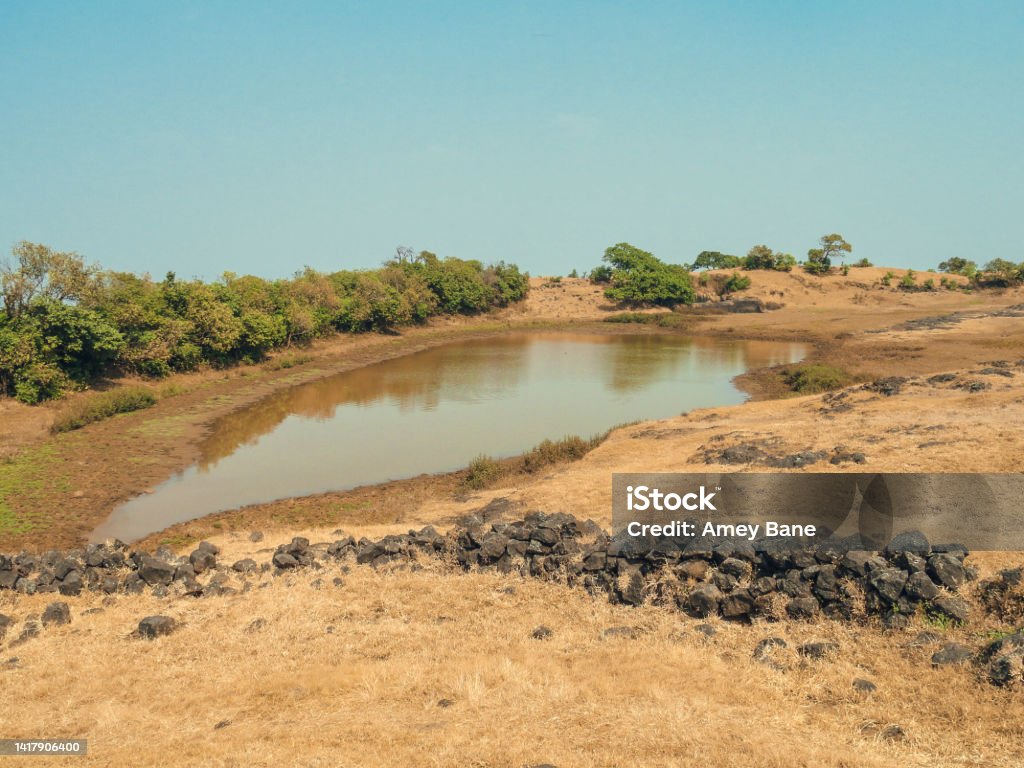 A Water Pond on a Mountain filled with muddy Water A afternoon shot of Water Pond on a Mountain filled with muddy Water with open blue sky. Ancient Stock Photo
