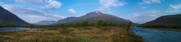 vaste paysage naturel panoramique de laponie avec pêcheur pêcheur et petite tente à la rivière bleue tjaktjajakka, kaitumjaure, forêt de bouleaux et montagne sanjartjakka. l’été dans la nature sauvage du nord de la suède. - forest road nature birch tree photos et images de collection