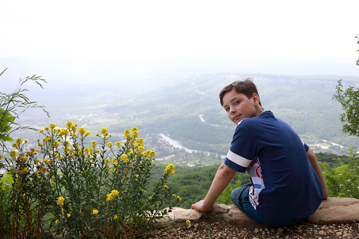 Kid resting on rock of Una-koz ridge in Caucasus, Adygea