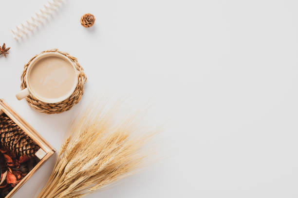 istock Cozy home desk table with coffee cup, wheat, box with dry petals, pine cones, on white background. Autumn composition. Flat lay, top view, copy space. Hygge, nordic style. 1417910746