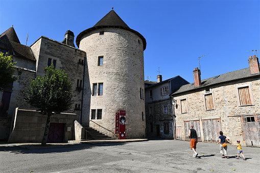Bourganeuf, France-08 06 2022:People passing near an old medieval tower in the town of Bourganeuf, Limousin region, Central France.
