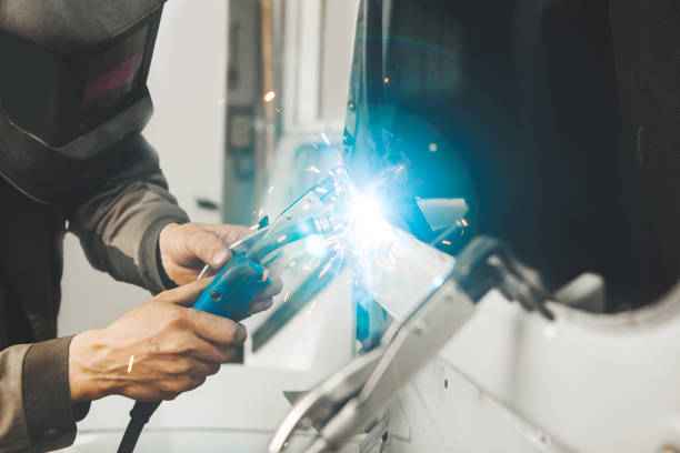 istock Welder in protective mask welds car body. 1417913272