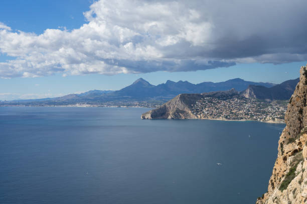 cielo nuvoloso e montagne blu sulla costa mediterranea in spagna - benidorm alicante spain headland foto e immagini stock