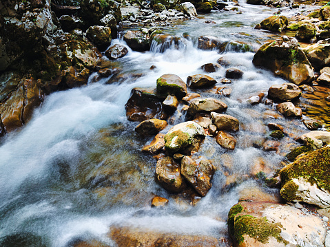 Long exposure of mountain stream flowing through mossy rocks