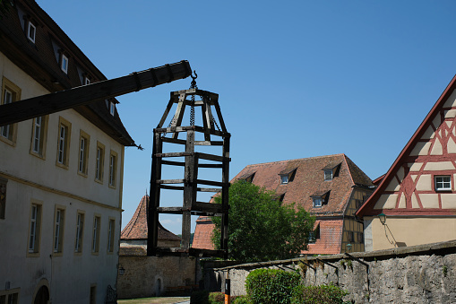 Courtyard of Medieval Crime Museum, wooden torture cage, device for torturing witches with water, historical buildings at old town, Rothenburg ob der Tauber, Bavaria, Germany