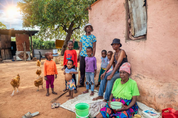 three generations three generations, granny, parents and kids outdoors in the yard of a house , village in botswana big family sunset stock pictures, royalty-free photos & images
