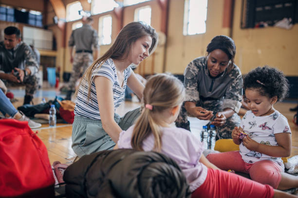 Soldiers with civilians after natural disaster Diverse group of people, soldiers on humanitarian aid to civilians in school gymnasium, after natural disaster happened in city. humanitarian aid stock pictures, royalty-free photos & images