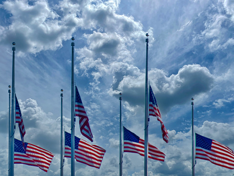 A group of United States of flags at half mast.  The position of a flag which is being flown some way below the top of its staff as a mark of respect for a person who has died.