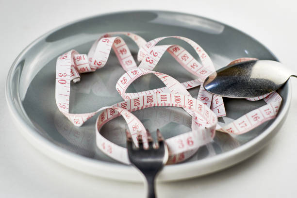 istock fork spoon and measuring tape on a gray plate diet concept 1417920693