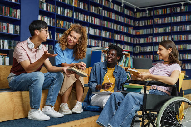 Diverse Group of Students Vibrant Diverse group of students in college library including young woman in wheelchair enjoying discussion school inclusivity stock pictures, royalty-free photos & images