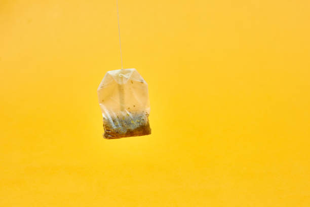 used tea bag on yellow background stock photo