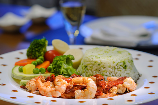 Shrimps with sun-dried tomatoes, rice and vegetables. Brazilian seafood.