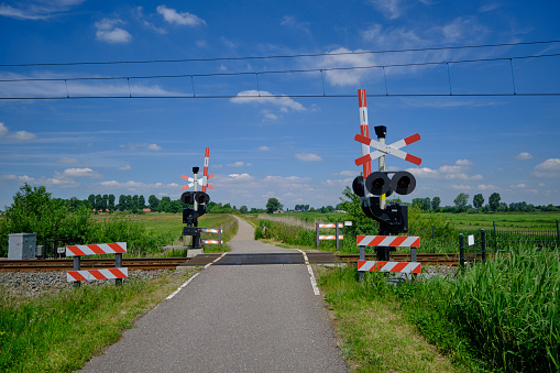 Guarded railroad crossing with open barriers, red warning light and cross of Saint Andrew in the NEtherlands.
