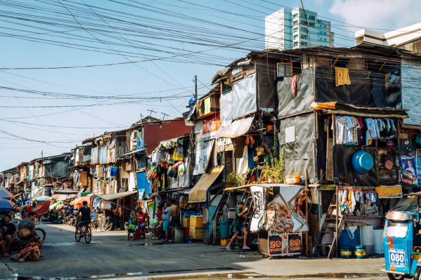 Manila, Philippines - March 05, 2022: Slums and illegal settlements scattered across the metropolitan area in downtown near the street. People do daily work.