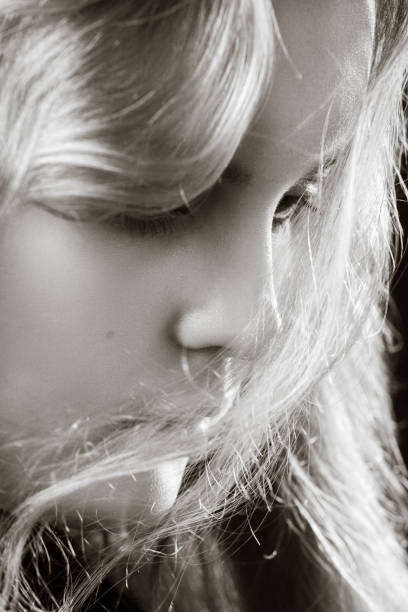 serious blond sad young long hair woman looking down closeup portrait, monochrome