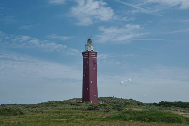 istock Square and solid Westhoofd lighthouse South Holland with beach, sand dunes, blue skies, dune flowers and puffy clouds. 1417928424