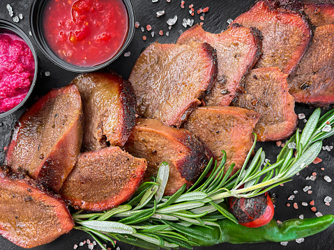 Sliced beef tongue with sauces and rosemary. Top view