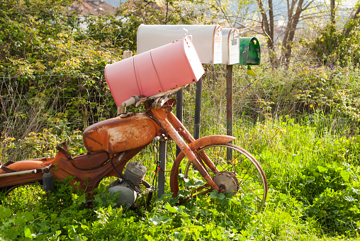 recycled retro mailboxes with old rusty vintage motorcycle in the countryside